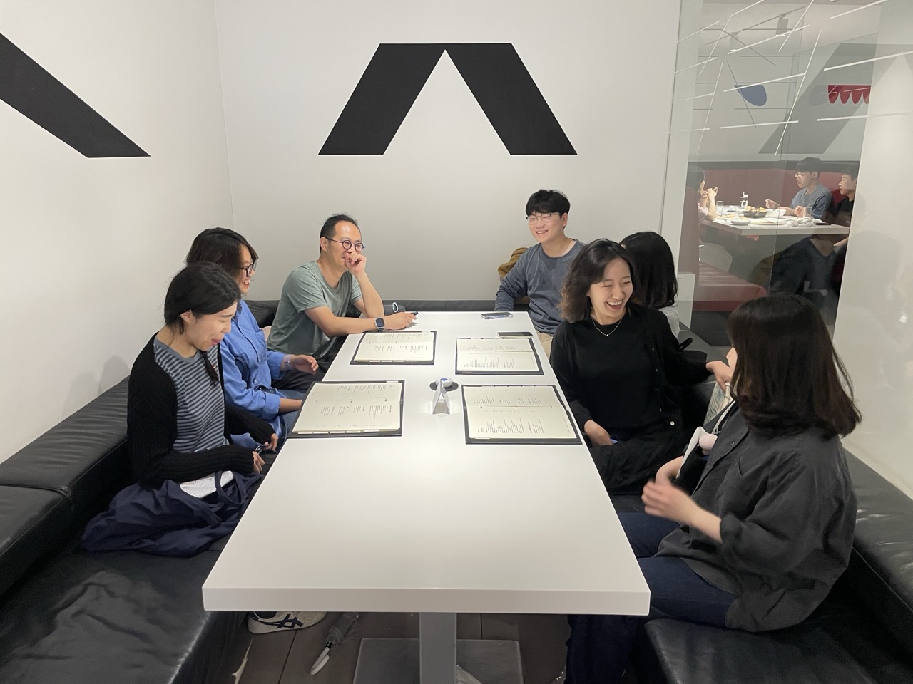 한국어 대체 텍스트: 큐레이팅 스쿨 서울 제 1학기 운영진과 코어 멤버로 이루어진 일곱 명의 사람이 이야기를 나누기 위해 검은색 가죽 소파와 흰색 테이블 주위에 둘러 앉아 있습니다. 재미있는 이야기가 오가는 순간이었는지, 모두 환하게 웃고 있습니다.
English Alt Text:
A group of seven individuals (staffs and core members of curating school seoul) seated at a white table in a café, engaged in conversation. They appear to be smiling and laughing, while discussing their thoughts and experiences related to an art exhibition.